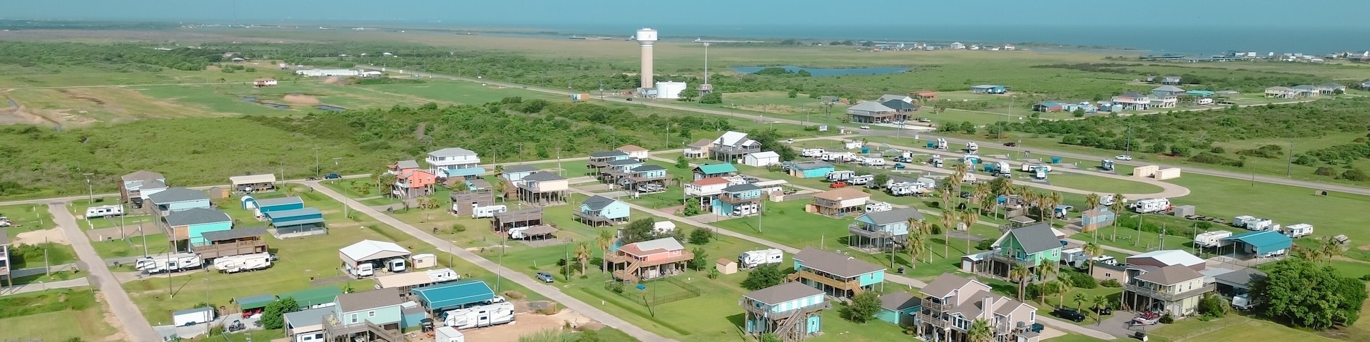 Une ville côtière avec des maisons, des camping-cars et un grand château d’eau qui domine le paysage.