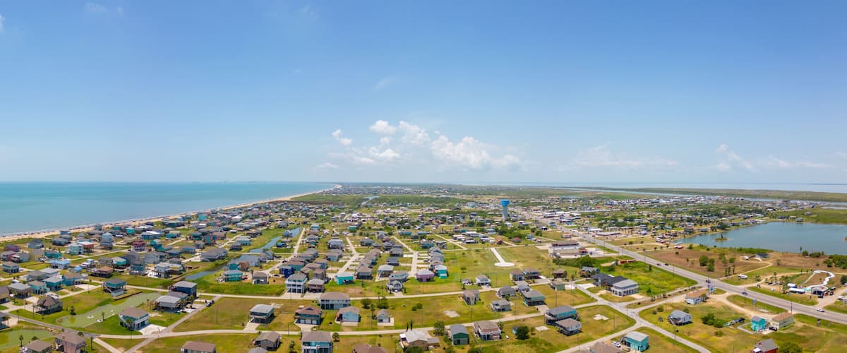 A coastal residential area with houses, a beach, and a body of water.
