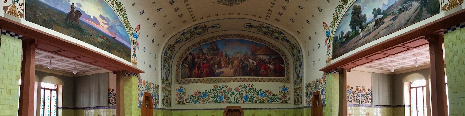 A spacious hall with ornate murals, a high ceiling, and patterned walls.