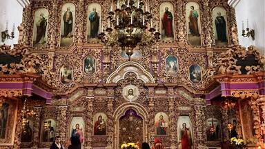 L’intérieur d’une église richement décorée, avec des sculptures complexes, un lustre central et des peintures religieuses.
