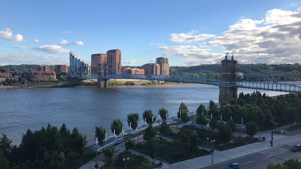 A river with a bridge, buildings, and a park with trees.