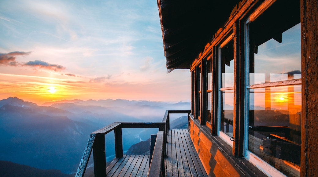 Un balcón de madera con vista a un paisaje montañoso al atardecer.