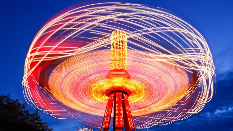 A brightly lit tower with a circular light trail against a night sky.