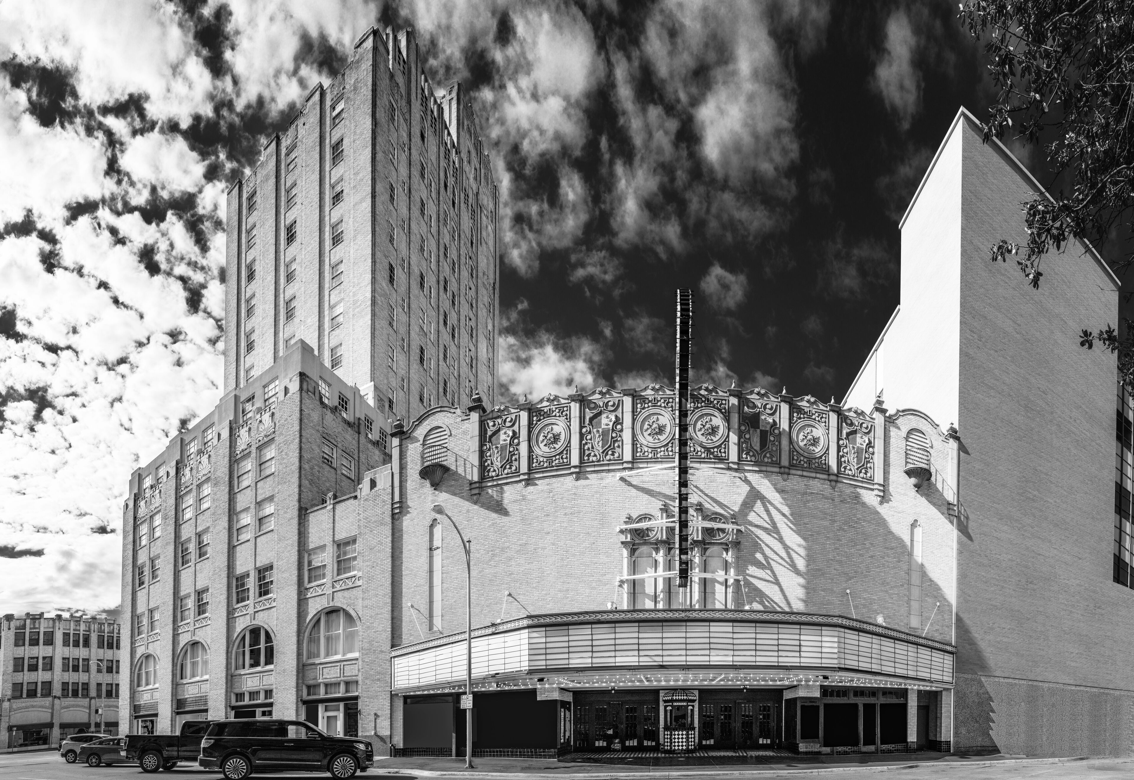 Abilene Texas city skyline and buildings and dramatic cloudscape at sunrise, black and white street landscape with view of facades of Spanish Colonial Revival architecture of theater and hotel