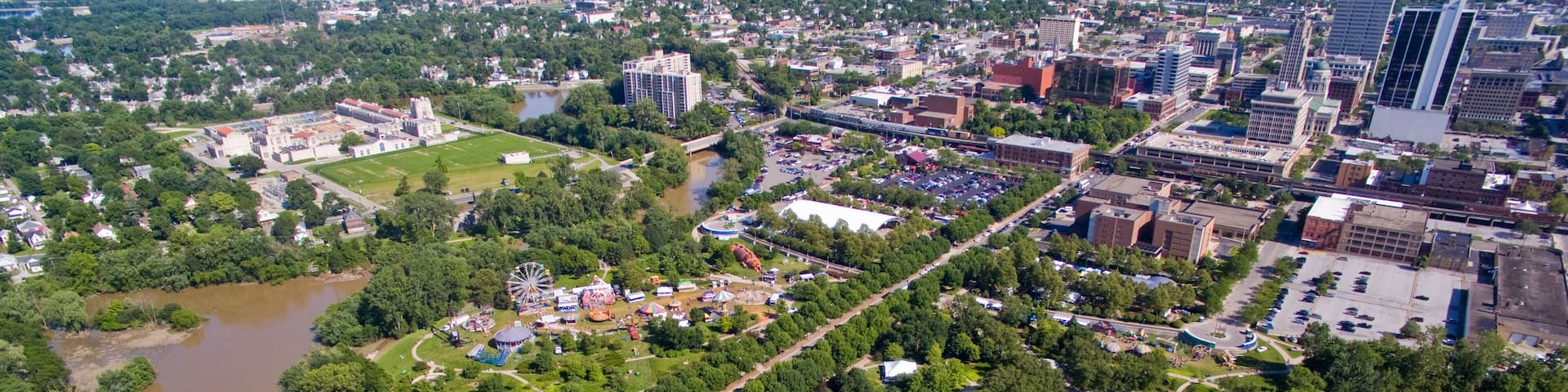A river meandering through a city with a bridge, green spaces, and buildings.