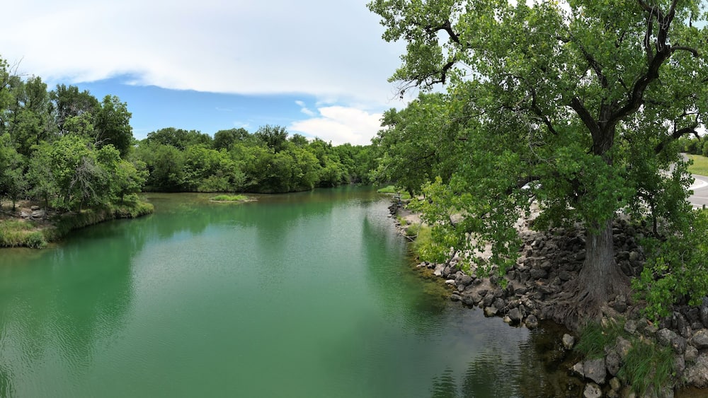 A river surrounded by dense green trees and a rocky shoreline.