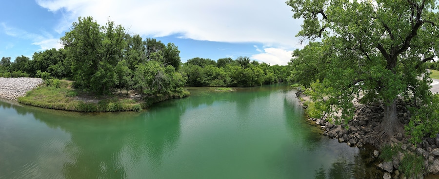 Un río rodeado de árboles verdes y una orilla rocosa.