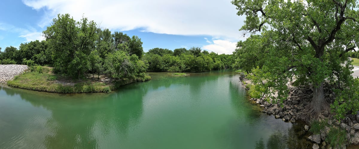 A river surrounded by dense green trees and a rocky shoreline.