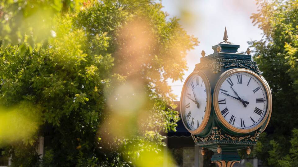 Los Altos, California, USA - August 30, 2024: Morning traffic passes the historic wrought iron clock in the historic downtown district.