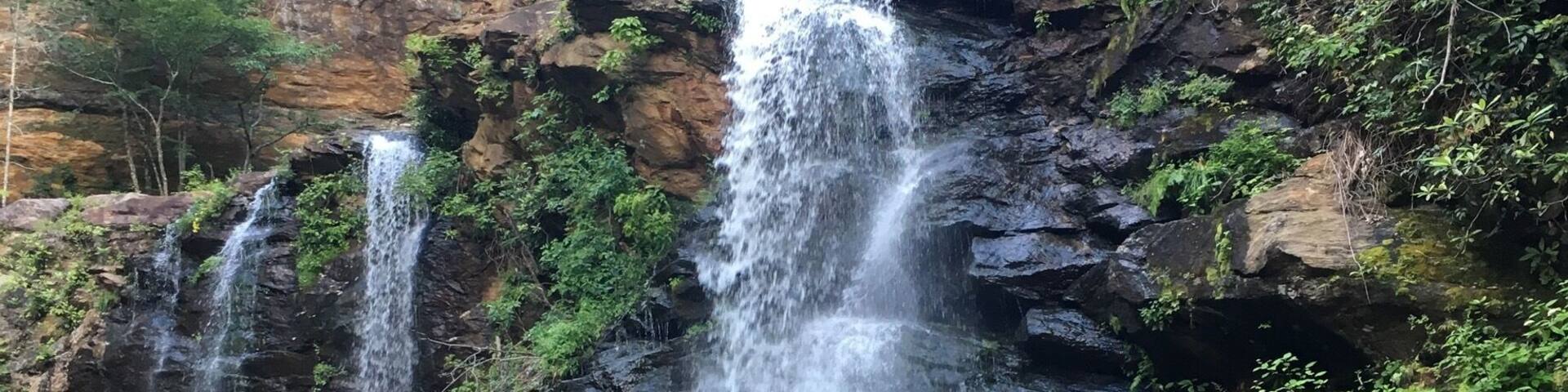 A waterfall cascading over rocky terrain surrounded by lush greenery.