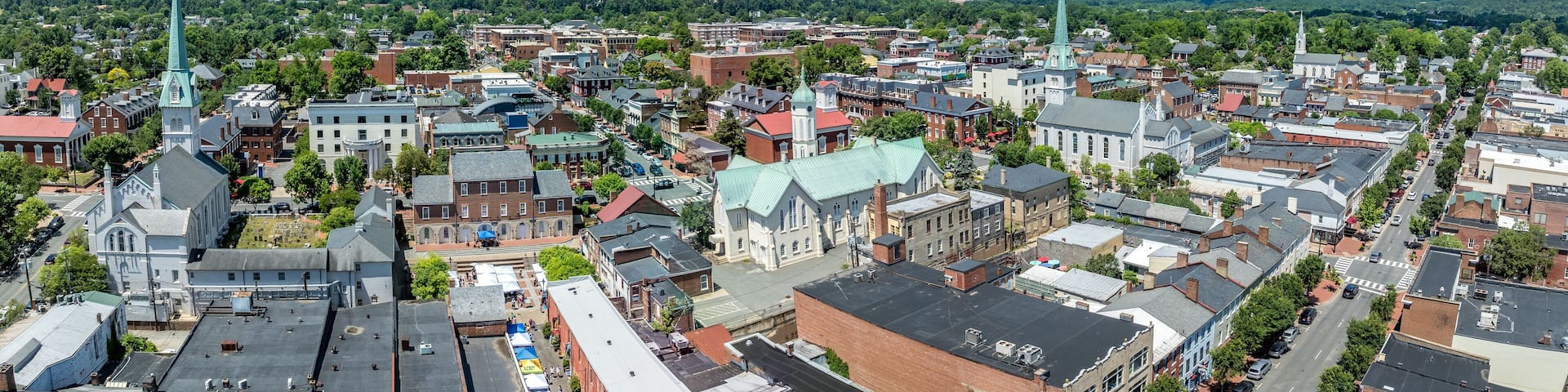 A town with historic buildings, a prominent church with a tall steeple, and a river in the background.
