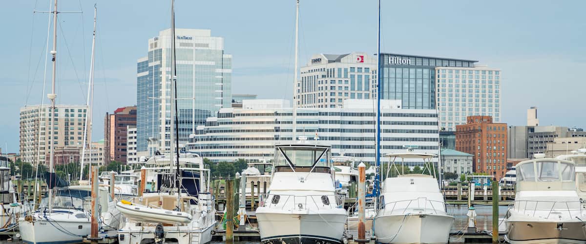 A marina with several boats docked, surrounded by modern buildings including a Hilton hotel and a SunTrust building.