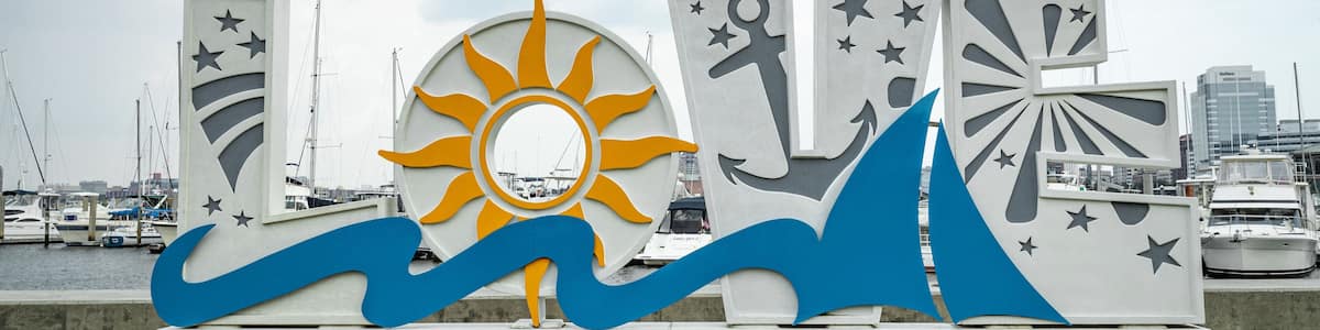 Schild am Wasser mit Sonne, Wellen und Sternen, unten die Aufschrift 'PORTSMOUTH'.
