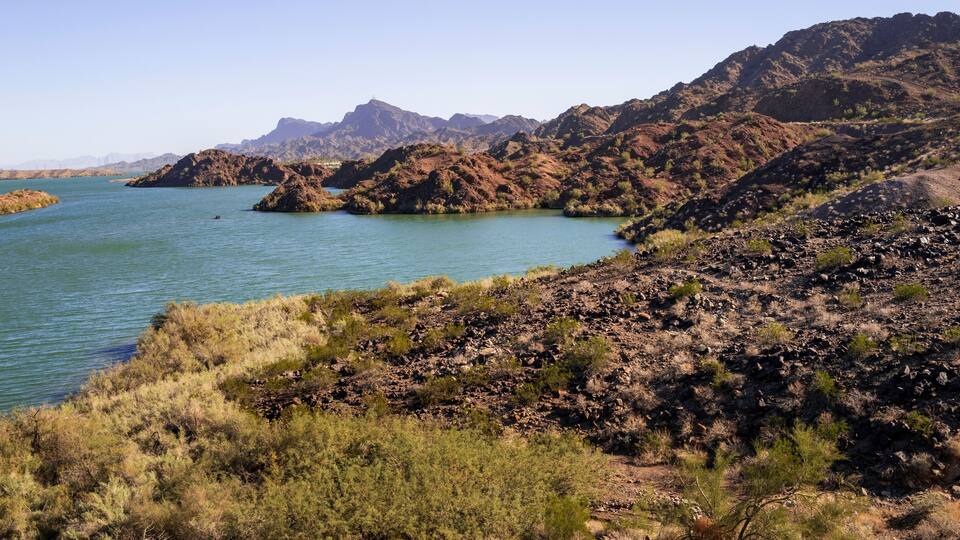 Tranquil southwestern desert wilderness landscape with red rock hill islands and blue water along the Colorado River near Havasu City, Arizona, USA