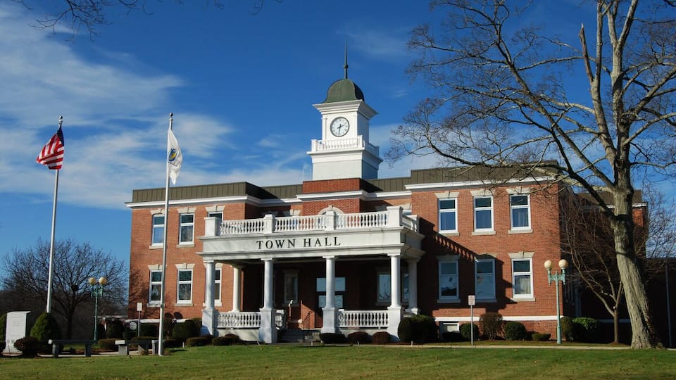 A brick building with a clock tower and a sign that reads "Town Hall."