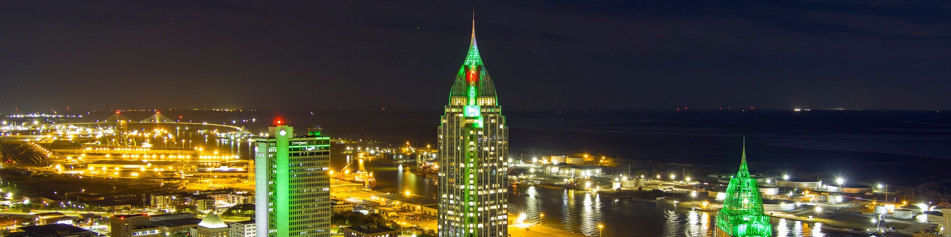 Paisagem urbana noturna com edifícios iluminados e um rio.