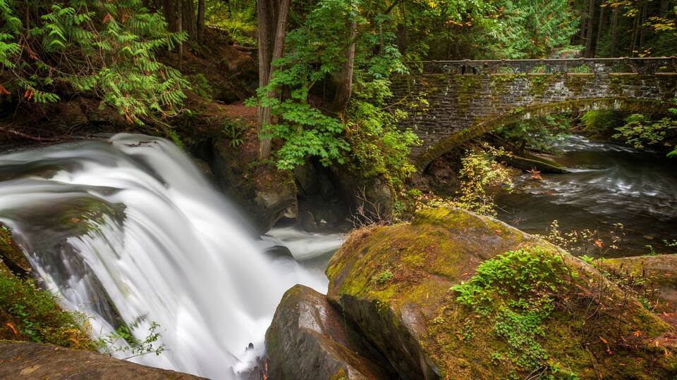 Waterfall in Whatcom Falls Park. A beautiful waterfall runs through this 241-acre park located in a rainforest environment with fir, maple and cedar trees. Autumn has arrived with colorful leaves.