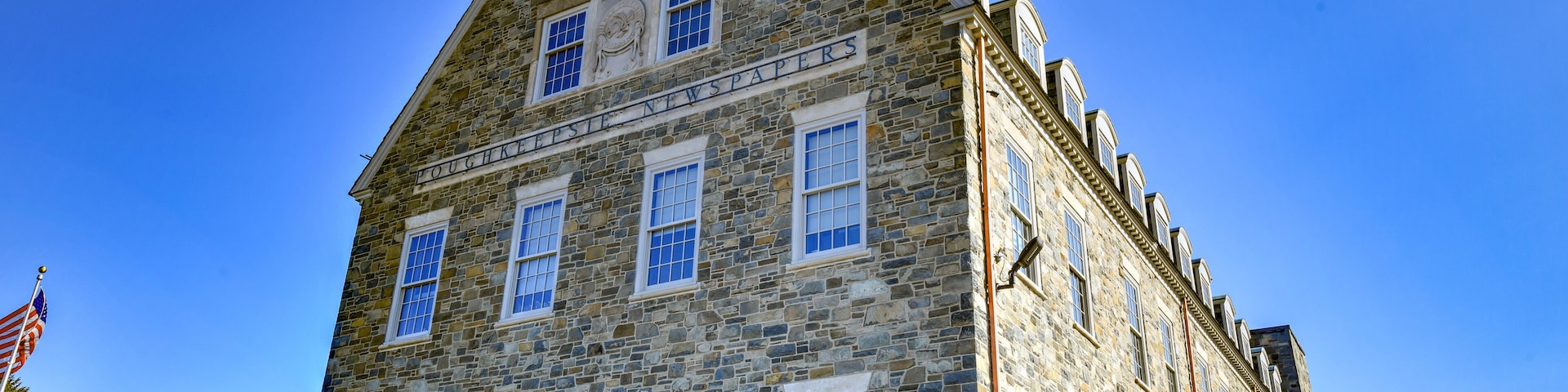 Ein historisches Steinhaus mit einem Schild, auf dem 'The Old Newspaper Building' steht.