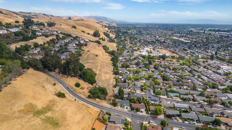 Aerial images over a neighborhood in Hayward, California with a blue sky and room for text.