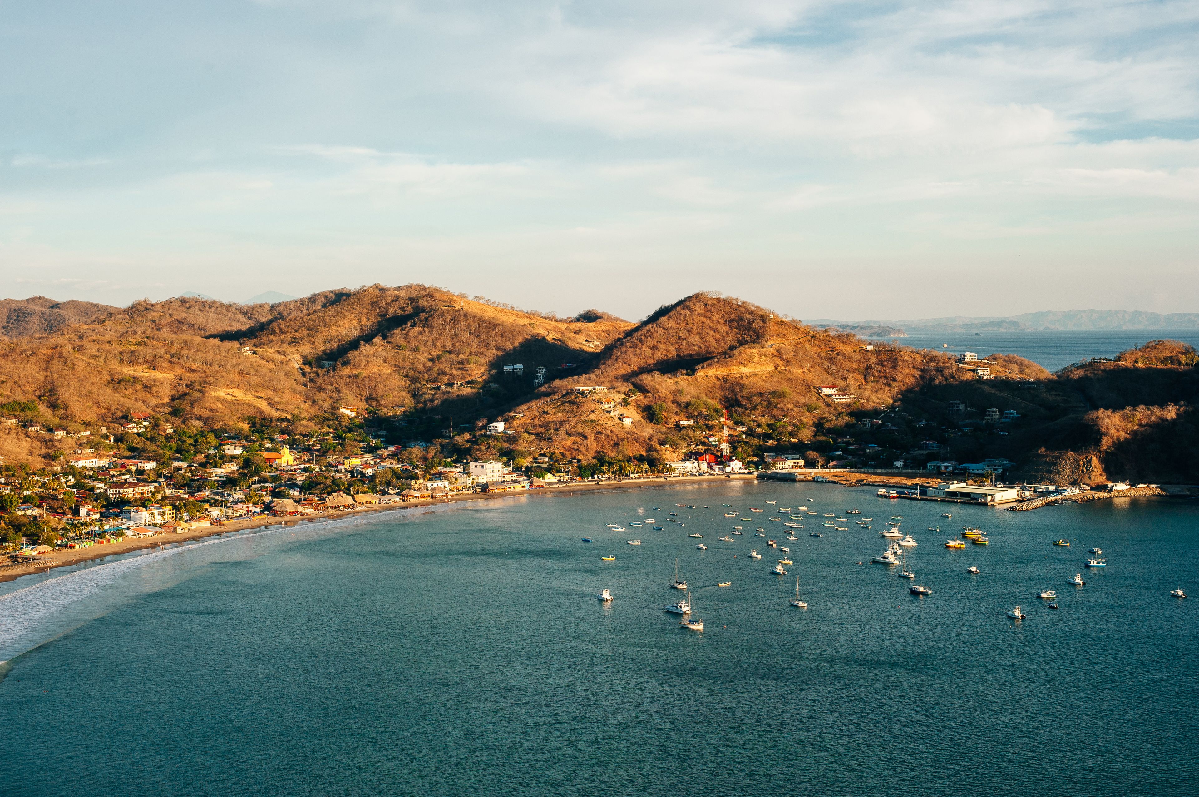 Un pueblo costero con una bahía llena de barcos, rodeado de colinas.