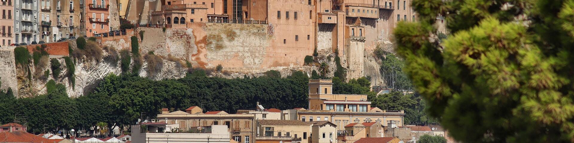 A cityscape with historic buildings, a prominent church with a dome, and a rocky hillside.