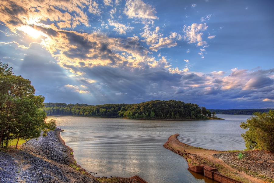 A calm lake with a wooden dock, surrounded by trees and a forested island.
