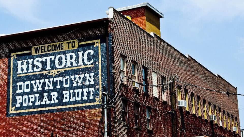A brick building with a sign that reads "Welcome to Historic Downtown Poplar Bluff."