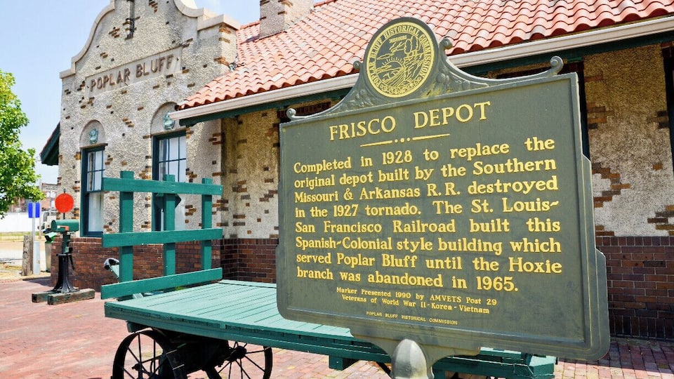 A historical marker sign for the Frisco Depot, detailing its construction in 1928, architectural style, and historical significance.