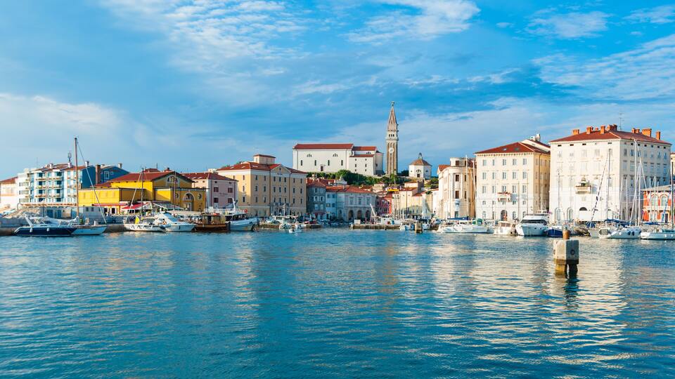 A harbor with boats, colorful buildings, and a prominent tower.