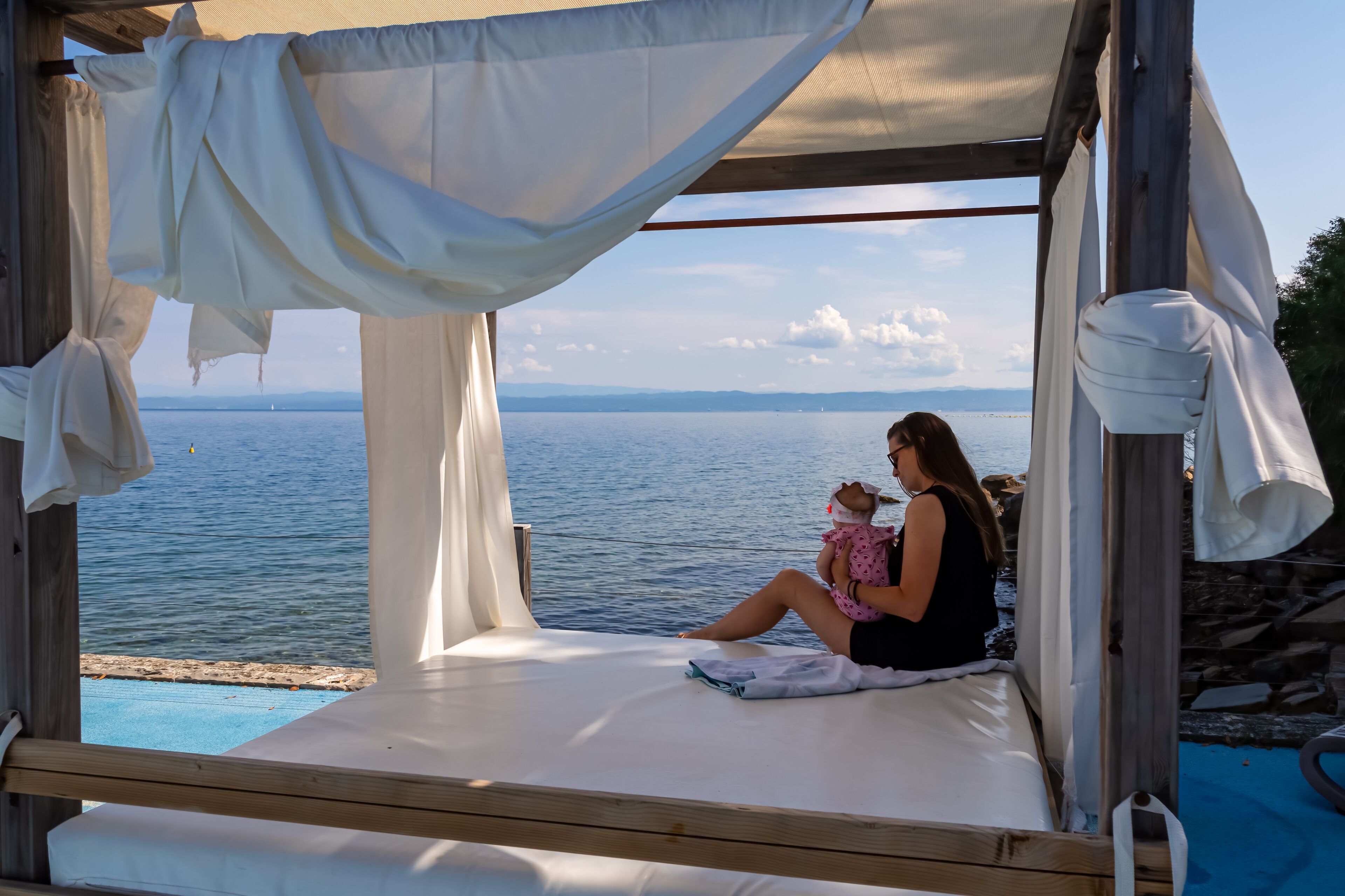 A wooden deck with a white canopy overlooking a body of water.