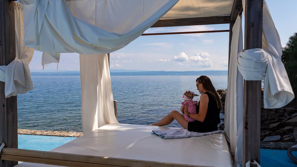 A wooden deck with a white canopy overlooking a body of water.