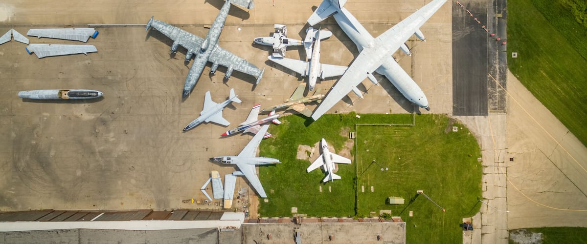 An aerial view of an airport with multiple aircraft parked on the tarmac, including large commercial jets and smaller planes.