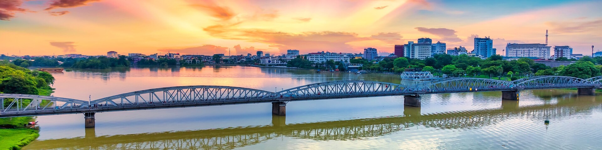 A bridge over a river with a city skyline in the background.