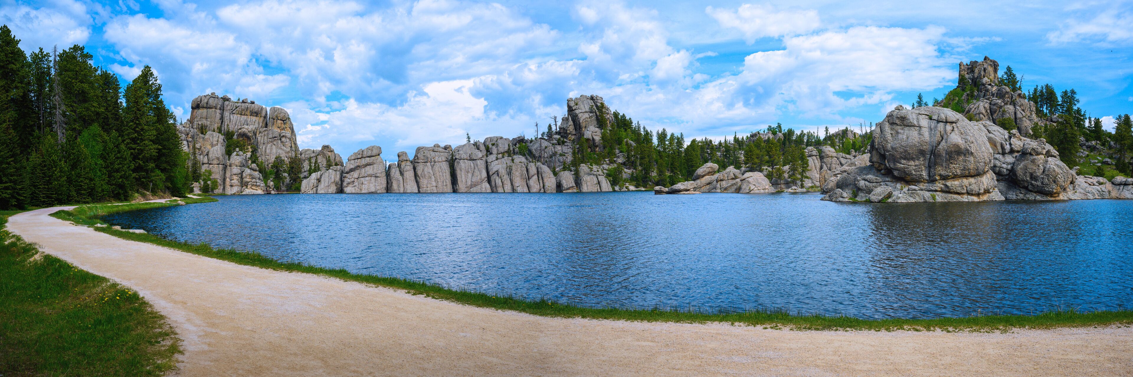 A lake surrounded by rocky cliffs and dense forest.