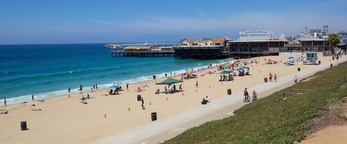 A crowded beach with people sunbathing and walking along the shore.