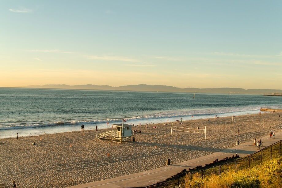 A nice beach way fewer crowds a nice view with hills in the background and the ocean.