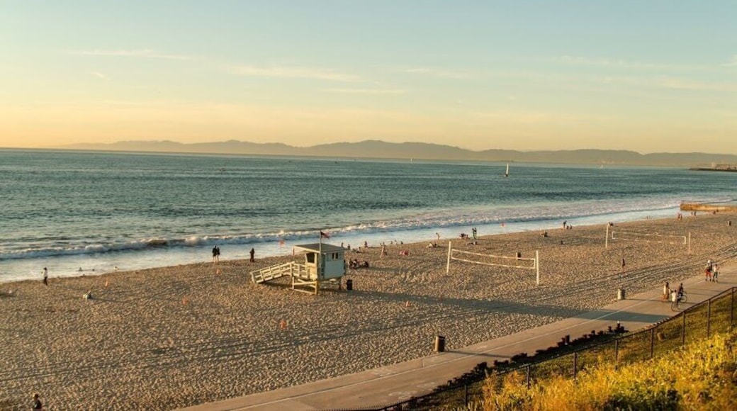 A nice beach way fewer crowds a nice view with hills in the background and the ocean.