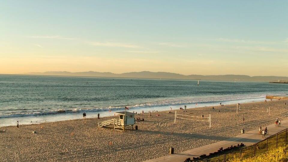 A nice beach way fewer crowds a nice view with hills in the background and the ocean.
