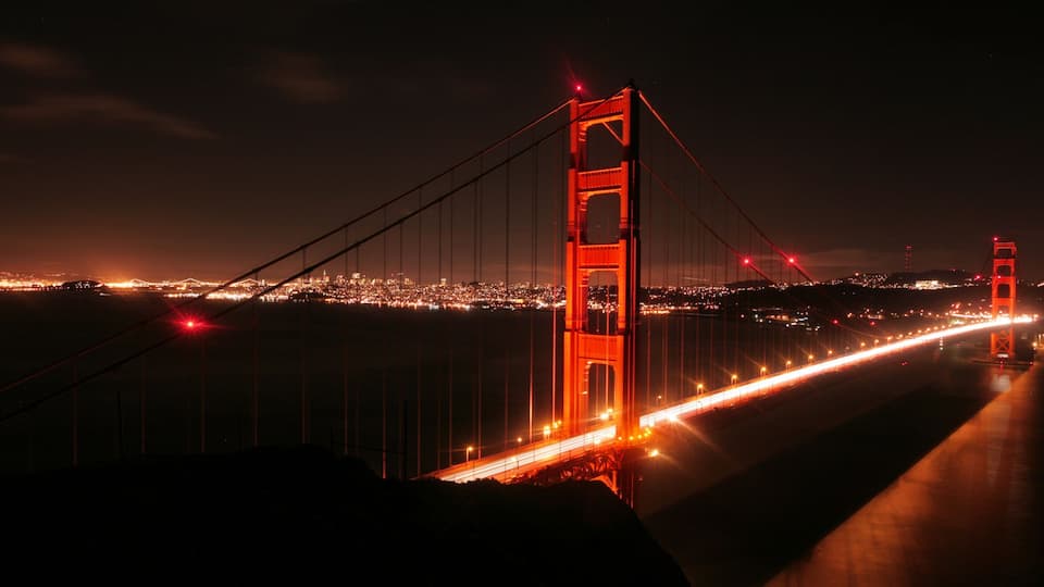 The Golden Gate Bridge at night with city lights in the background.