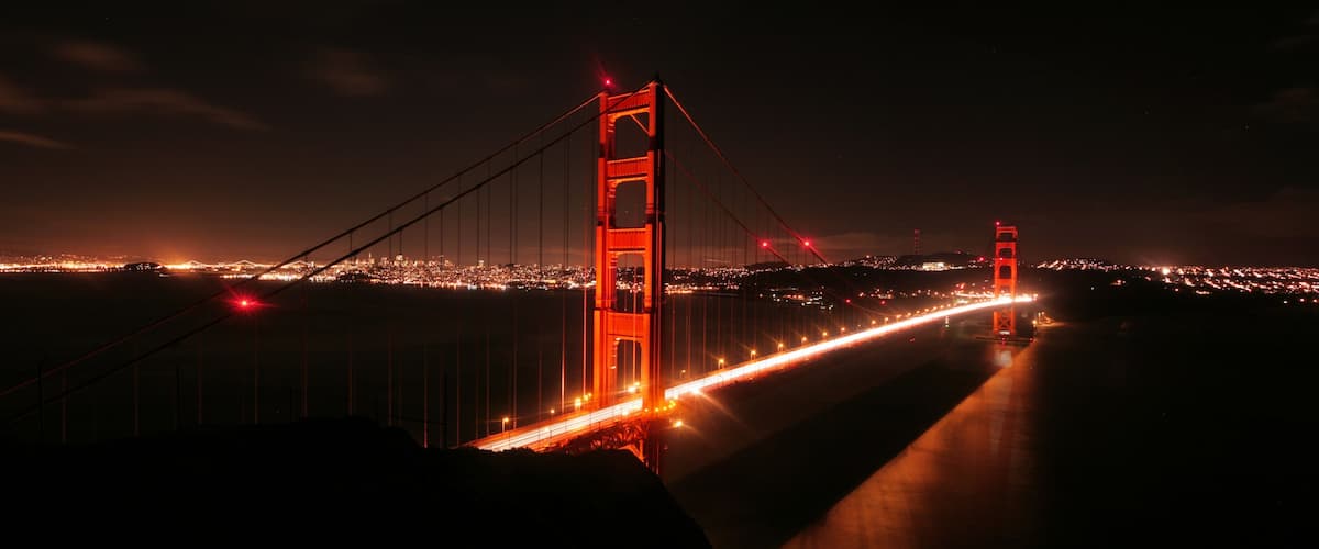 The Golden Gate Bridge at night with city lights in the background.