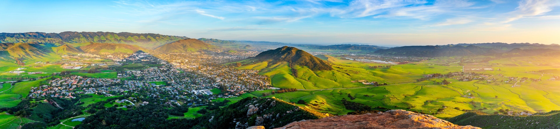 A mountainous landscape with a town nestled in the valley, a prominent hill, and a river flowing through the scene.