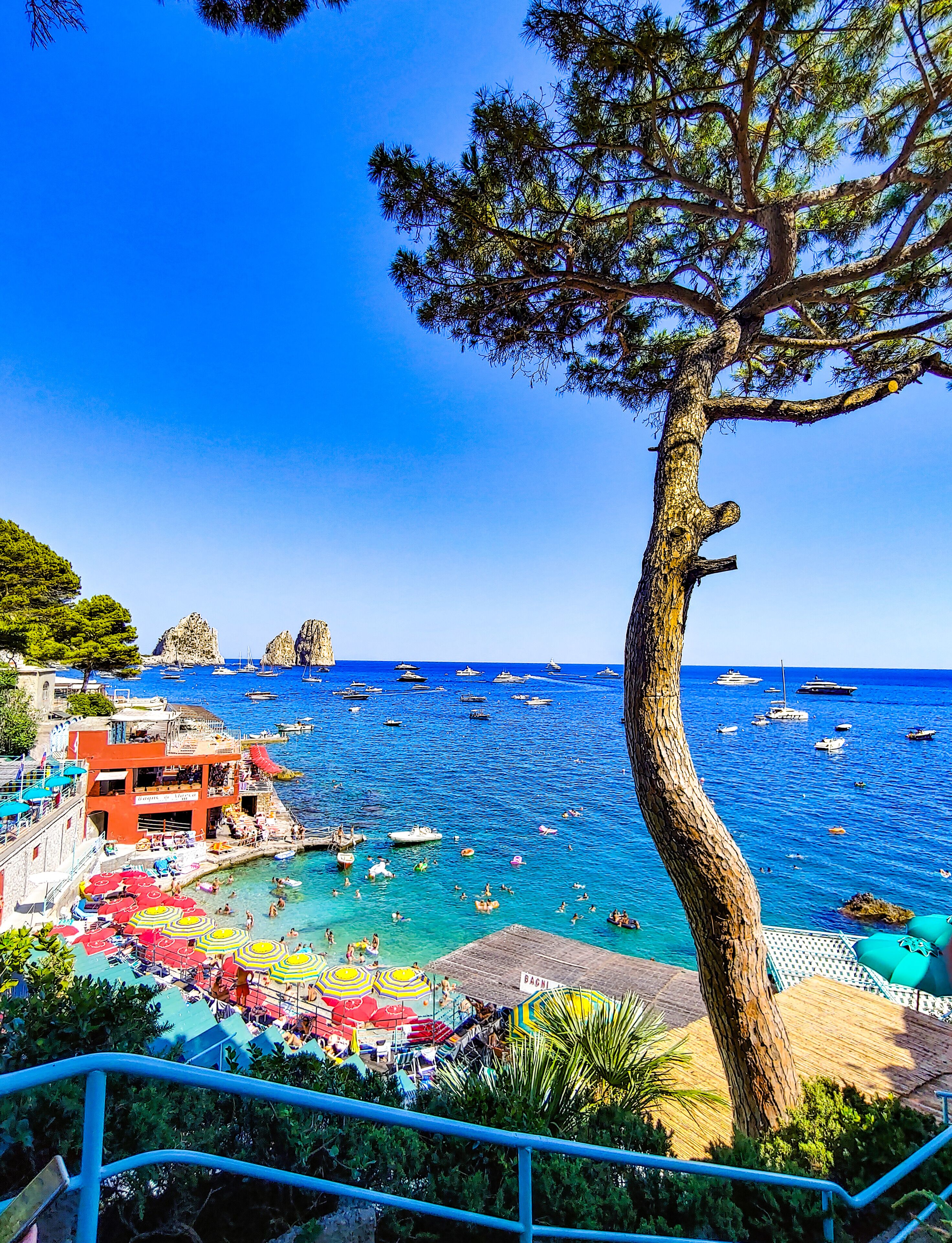 Un pueblo costero con un mar azul cristalino, sombrillas de colores y barcos.