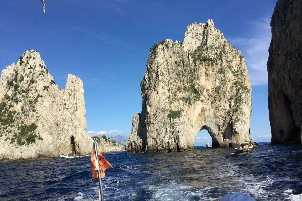 A boat navigating through a narrow waterway flanked by large rock formations with an archway.