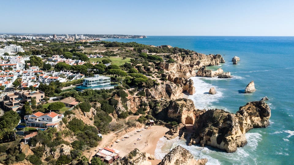 A coastal town with rocky cliffs, a beach, and residential buildings.