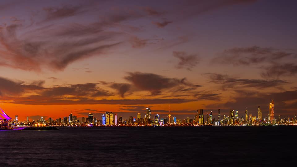 Stunning Kuwait City Skyline at Night with Illuminated Marina Waves and Vibrant Sunset Reflections Over the Arabian Gulf