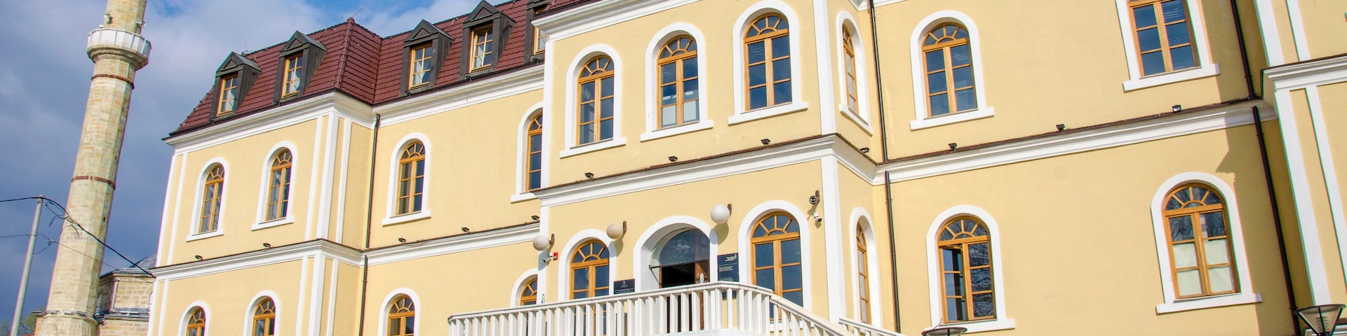 A historic building with a red-tiled roof, multiple arched windows, and a prominent tower.