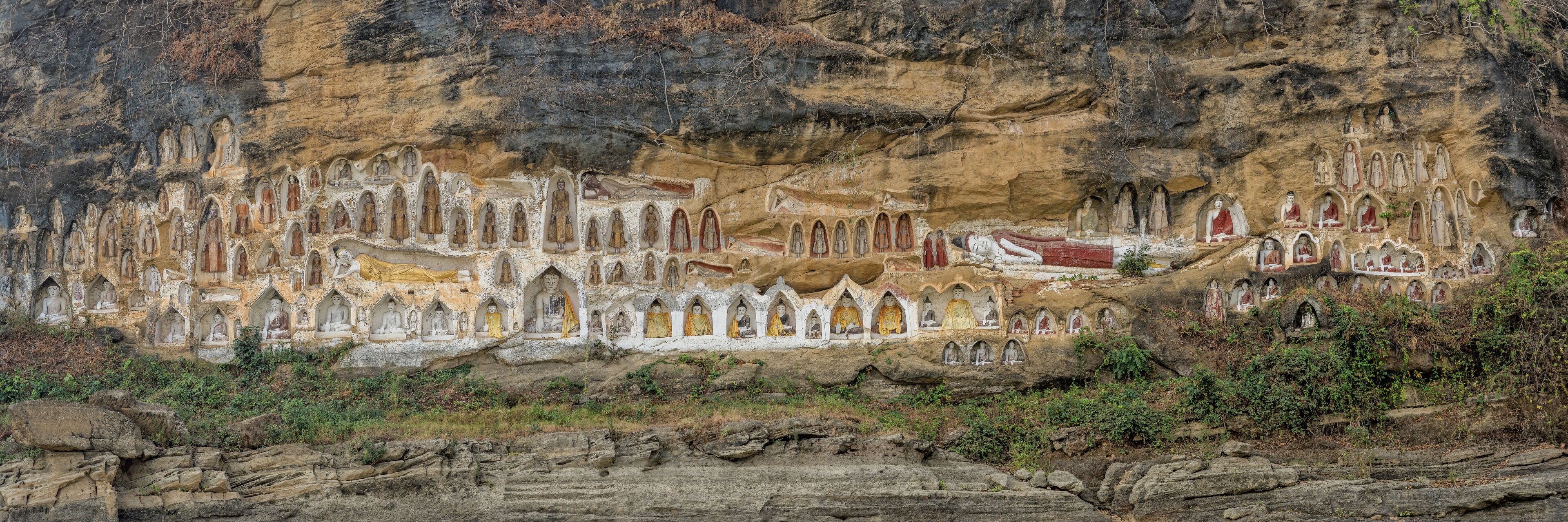 A cliffside with numerous carved Buddha statues.