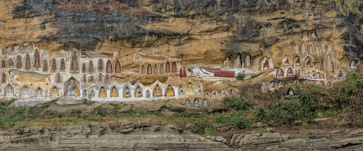 A cliffside with numerous carved Buddha statues.