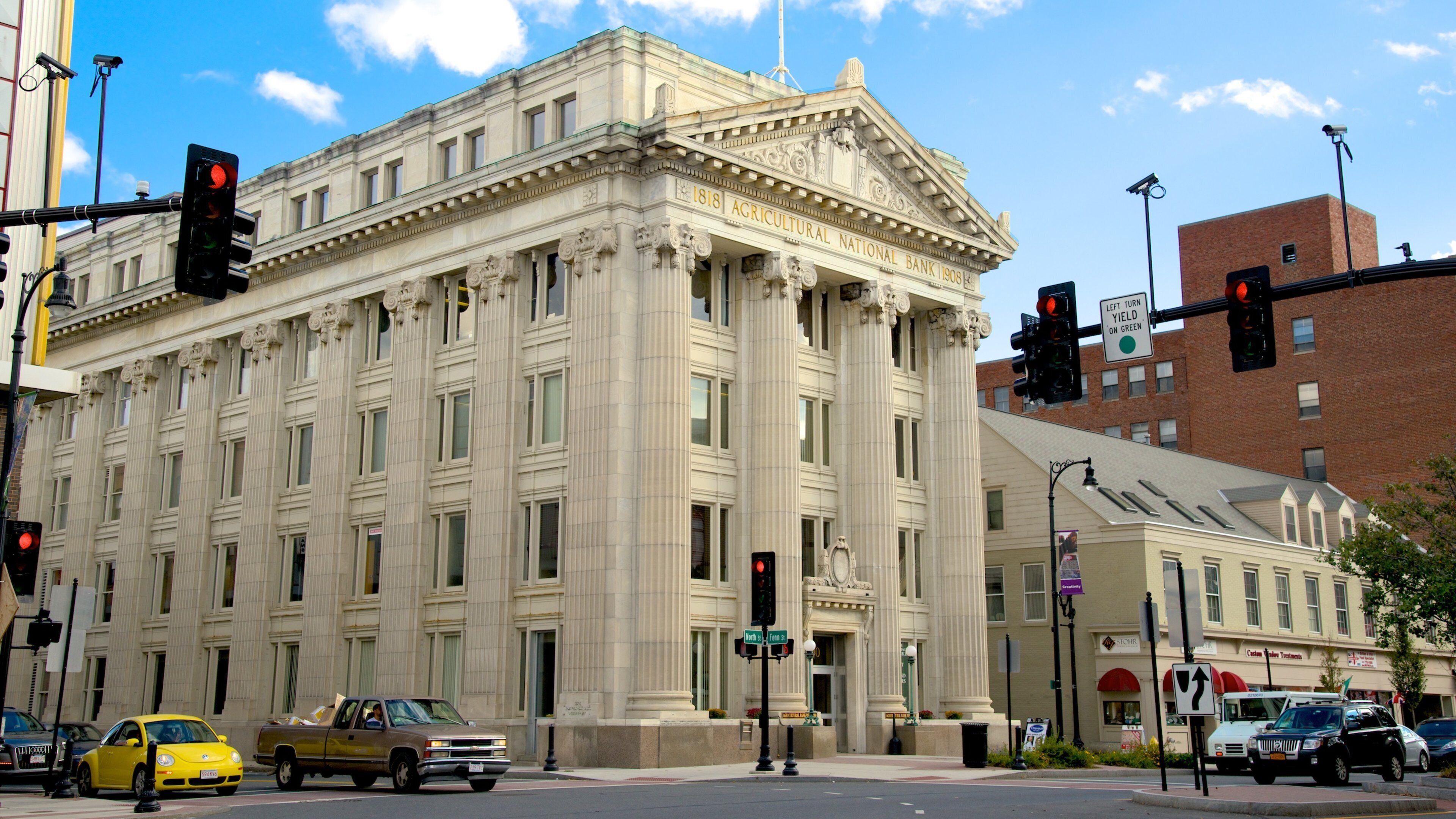 A historic building with classical architecture, a traffic light, and a yellow taxi.