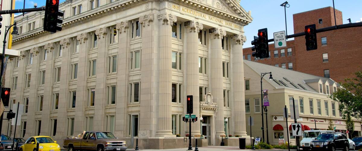 A historic building with classical architecture, a traffic light, and a yellow taxi.